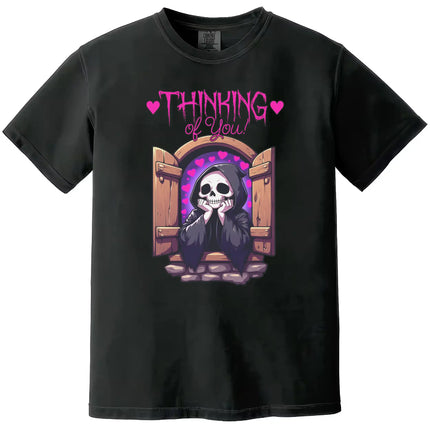 Thinking of You’ t-shirt in black, cute grim reaper leaning from castle window with hearts, dark humor romantic graphic tee.