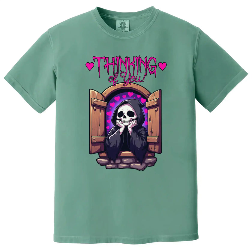 Cute dark humor tee in green, grim reaper in castle window with hearts and ‘Thinking of You’ text, quirky romantic design