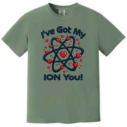 Green science pun Valentine shirt flat lay showing atom design and “I’ve Got My Ion You” lettering for nerdy couples.