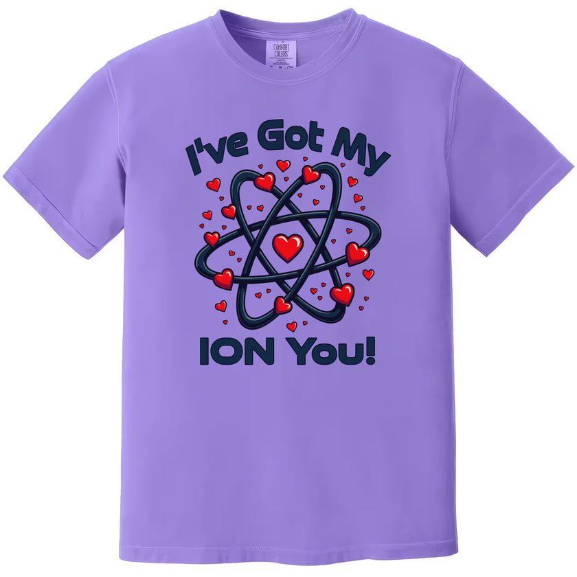 Purple “I’ve Got My Ion You” shirt flat laid, showcasing a cute nerdy chemistry Valentine design.
