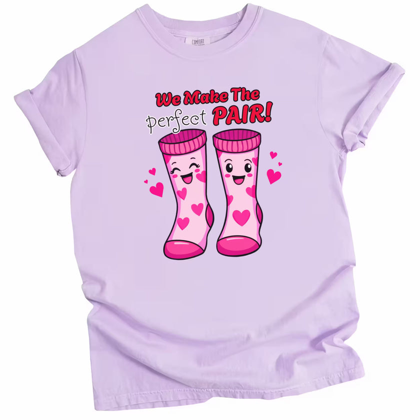 We Make the Perfect Pair t-shirt with Valentine socks graphic, light purple shirt flat lay, playful love-themed unisex tee for Valentine’s Day gifting