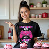 Female model wearing black “Emotionally AFK” gamer Valentine’s tee, with cupcakes in kitchen, playful and festive.