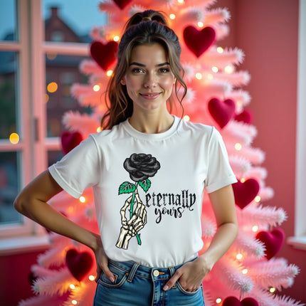 Female model wearing white Eternally Yours gothic Valentines tee with skeleton hand and black rose, standing in living room in front of pink Valentines tree