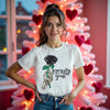 Female model wearing white Eternally Yours gothic Valentines tee with skeleton hand and black rose, standing in living room in front of pink Valentines tree