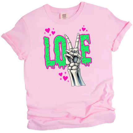 Valentine’s Gothic LOVE t-shirt flat lay in pink with edgy skeleton hand peace sign and green dripping letters.