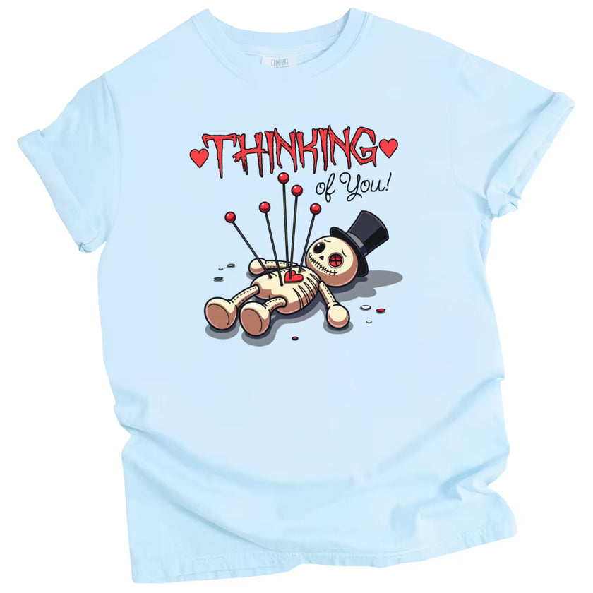 Thinking of You t-shirt with voodoo doll graphic, blue shirt flat lay, playful gothic Valentine’s aesthetic, women’s graphic tee for Valentine’s Day gifting