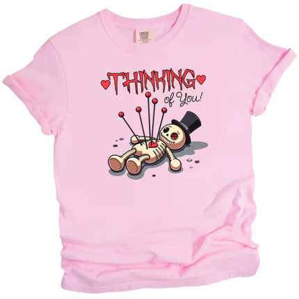 Thinking of You Valentine’s t-shirt with voodoo doll art, pink shirt flat lay, cute dark humor aesthetic, love themed graphic tee