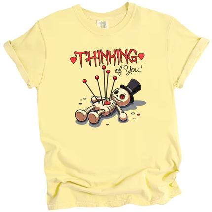 Thinking of You graphic t-shirt with voodoo doll, yellow shirt flat lay, playful Valentine’s aesthetic, fun love themed tee