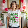 Female model wearing white “I ♥ U” Valentine’s tee, standing in her living room, playful camo heart detail
