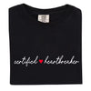 Minimalist Certified Heartbreaker tee in black with red heart and white script writing, flat lay on white background.