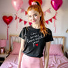 Woman wearing black “I’m So In Love With You” t-shirt in a Valentine’s Day decorated bedroom, romantic love graphic tee styled for cozy seasonal wear