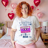 Female model wearing white “We’re the Perfect Mix” Valentine’s tee with pink cassette tape in festive bedroom