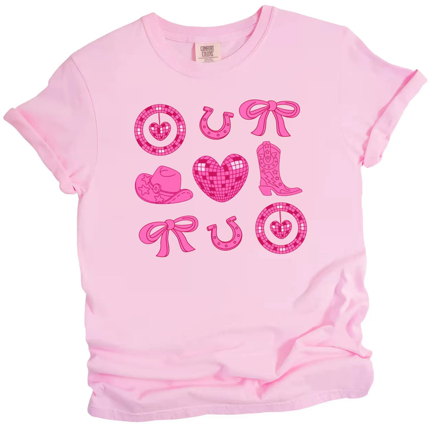 Pink cowgirl coquette Valentine’s tee with boots, hearts, and hats on a white background