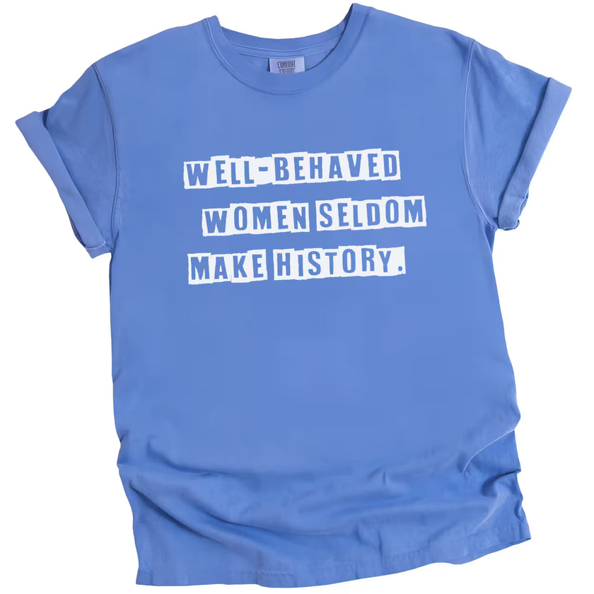 Blue “Well-Behaved Women Seldom Make History” t-shirt flat lay highlighting empowering women’s statement with bold lettering