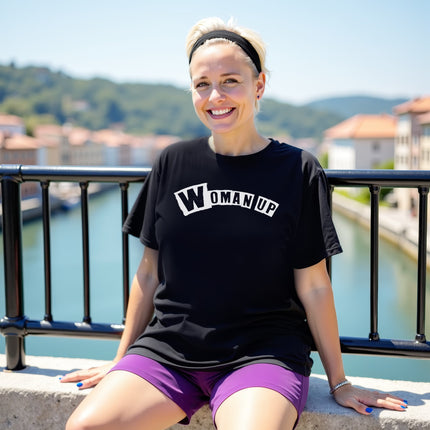 Female model wearing black “Woman Up” t-shirt sitting casually, showing confident and empowering girls-supporting-girls energy